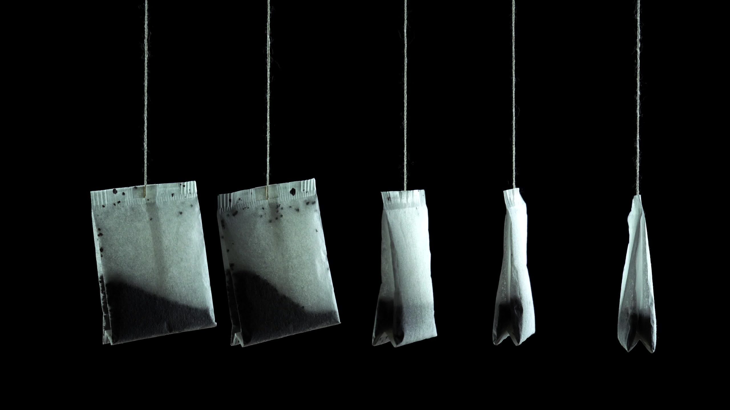 Tea envelopes hanging on the threads in the dark