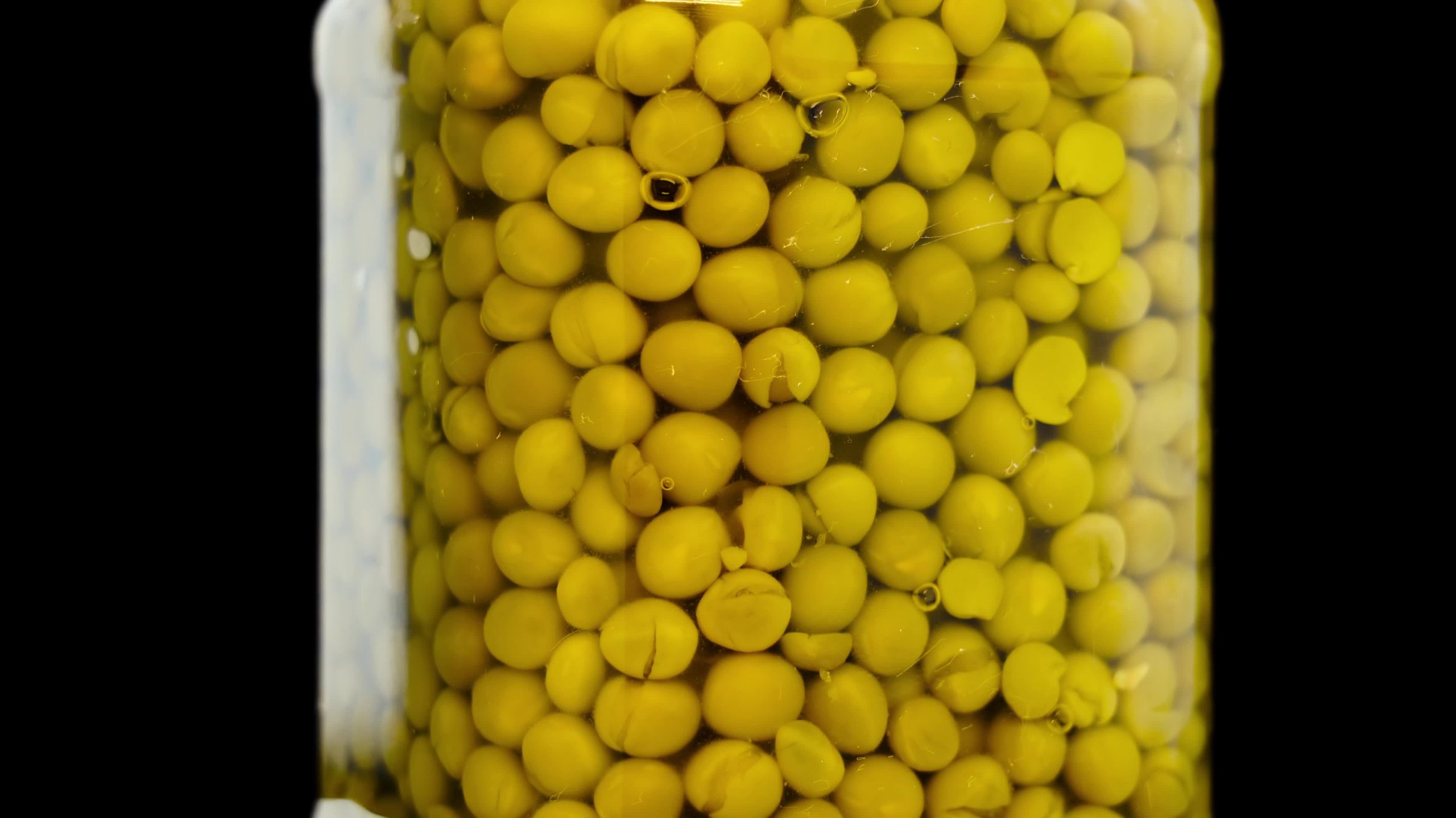 Barattolo di vetro di piselli dolci in scatola in marinata piccante sul nero