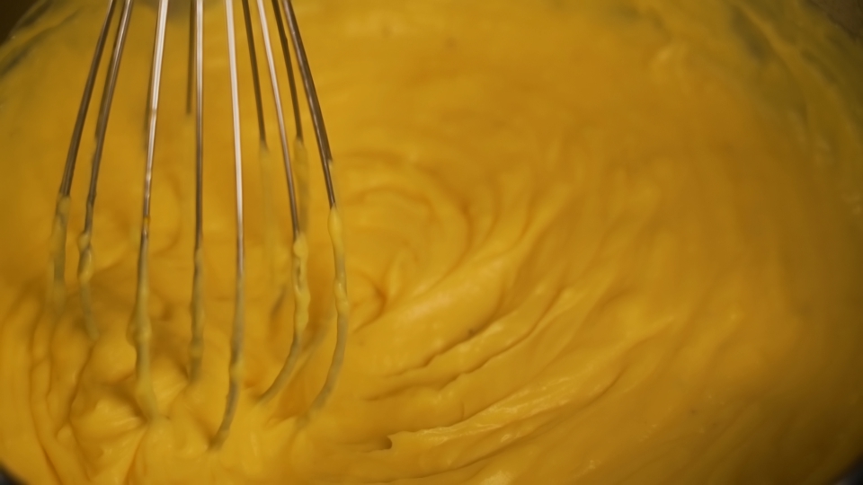 Impastare la pasta cruda con la frusta nel contenitore al primo piano leggero