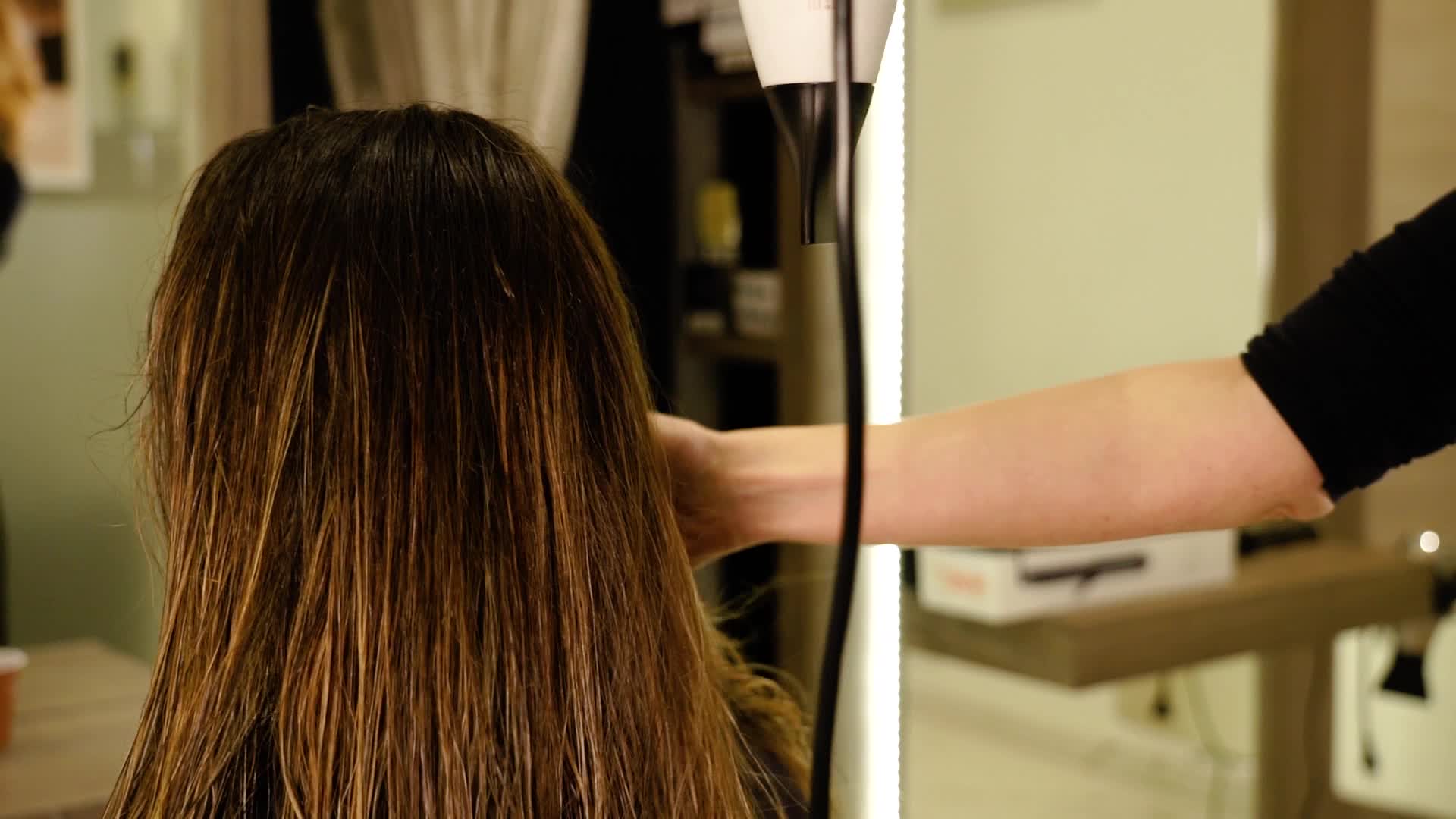 La parrucchiera asciuga i capelli con il phon