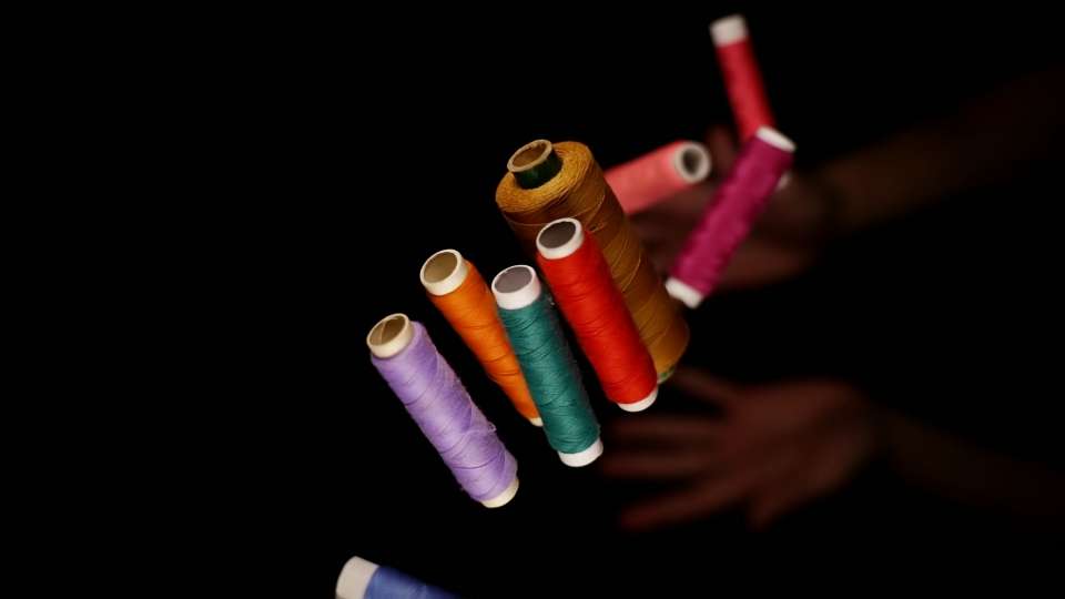 Tossed colorful thread spools on dark background