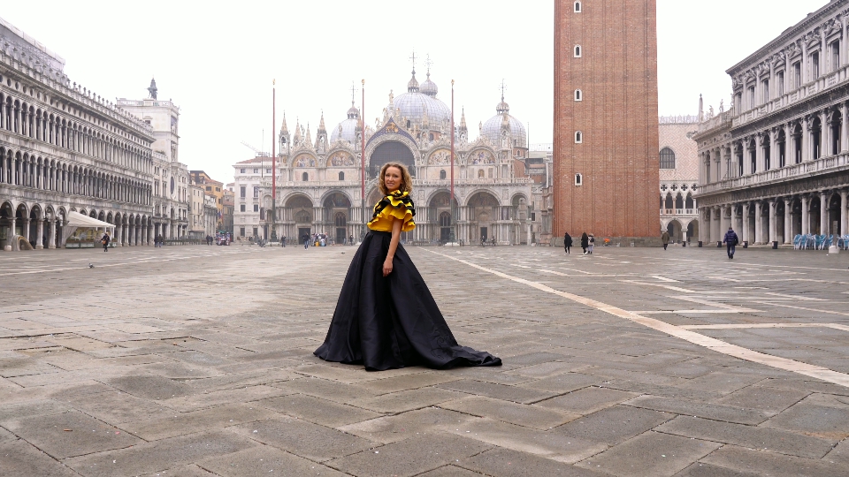 Pretty lady in long dress poses at deserted st marks square