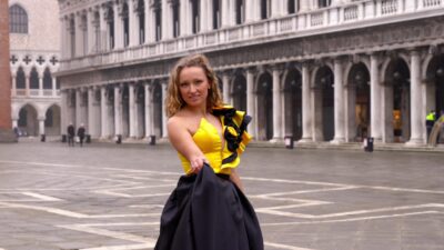 Professional model wears designer carnival dress holding hem