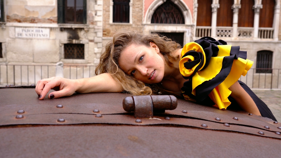 Lady with flounce on dress leans on old metal well cover