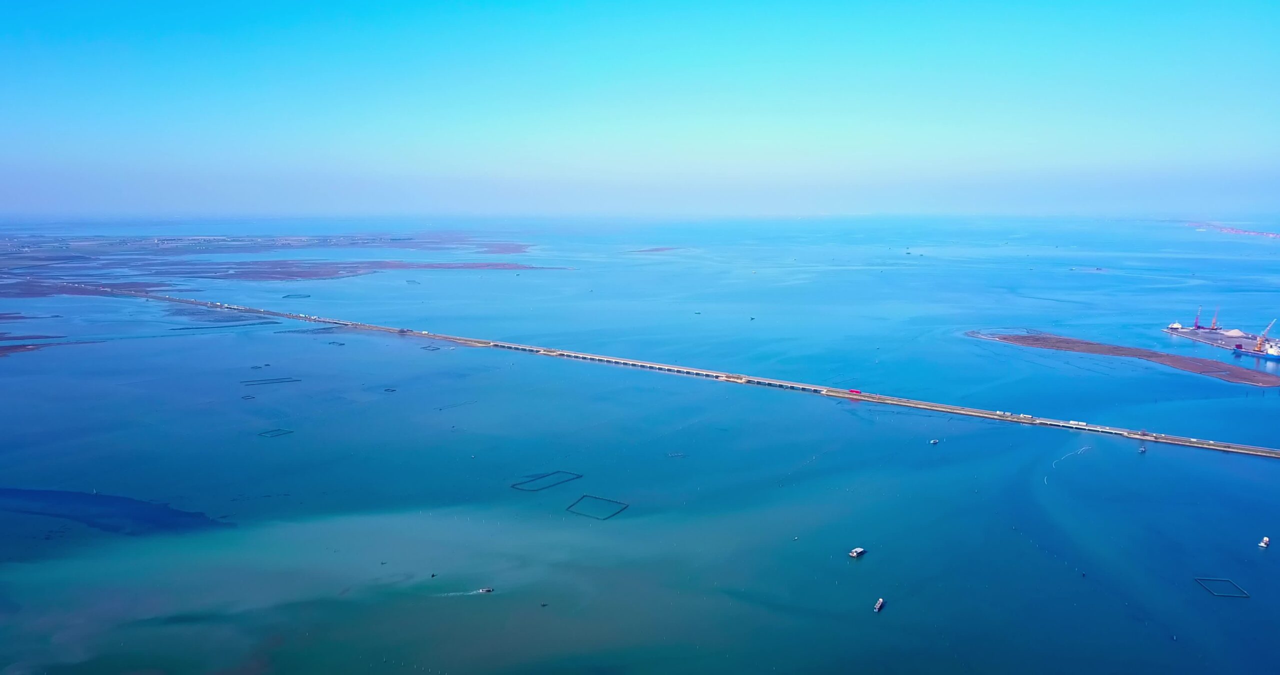 Panorama lagunare con acqua blu attraversato da strada sul polder
