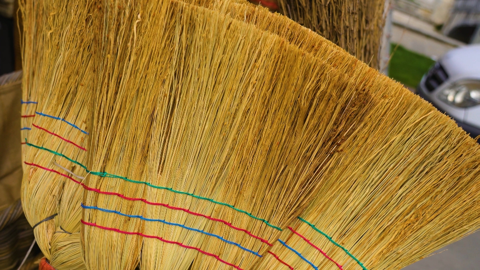 Handmade reed brooms with colored strips in marketplace