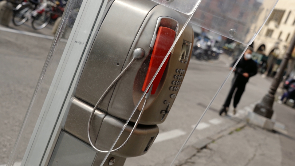 Small phone booth against person in mask on scooter and cars