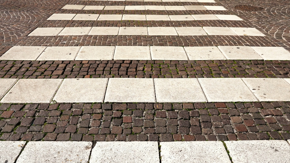 Passaggio pedonale bianco piastrellato con grandi pietre bianche su strada asfaltata