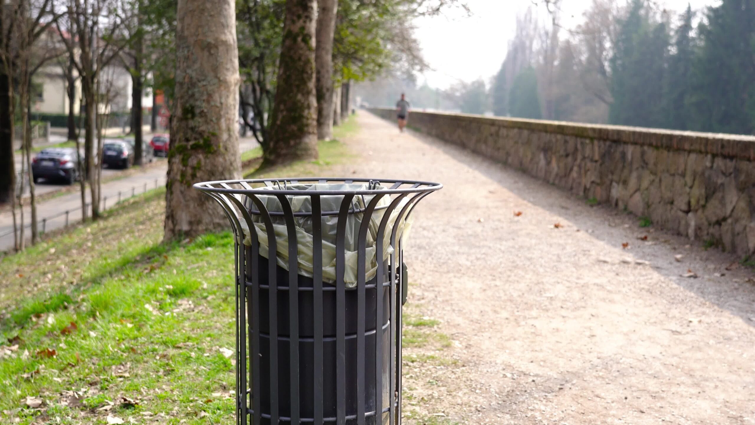 Elegante bidone della spazzatura in metallo contro l’uomo che corre sfocato