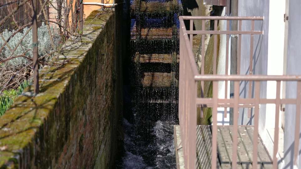 Obsolete large wooden watermill wheel rotates on canal
