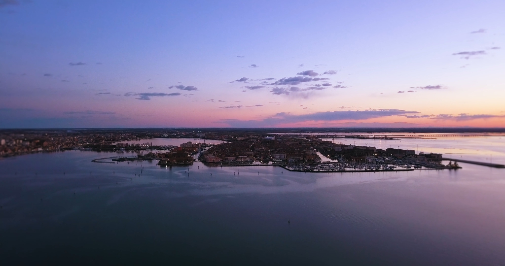 Purple Venetian lagoon against large city under sunset sky