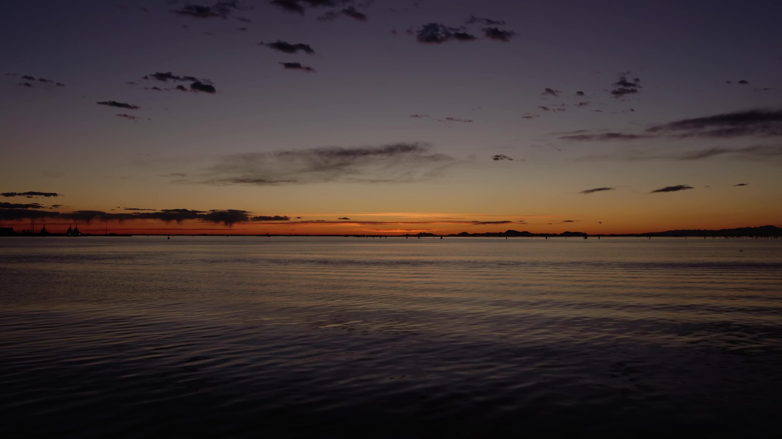Mare con acqua increspata con uccelli che volano in cielo al tramonto