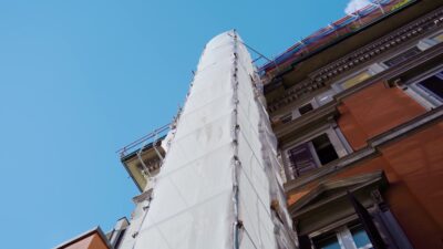 Old building under reconstruction with scaffolding fabric