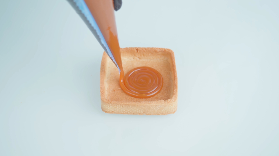 La persona riempie il biscotto con il disegno al caramello con la tasca da pasticcere