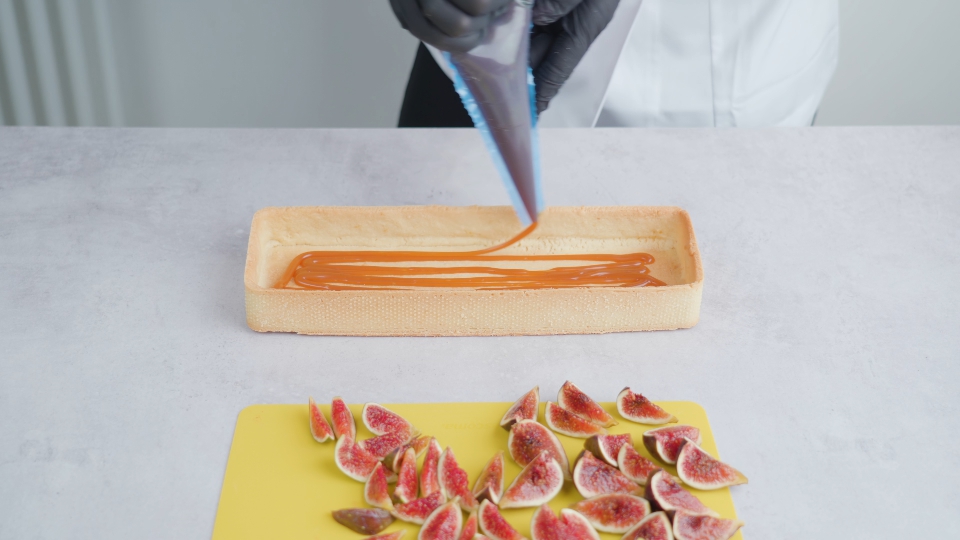 La persona tiene la tasca da pasticcere e riempie il biscotto con salsa al caramello