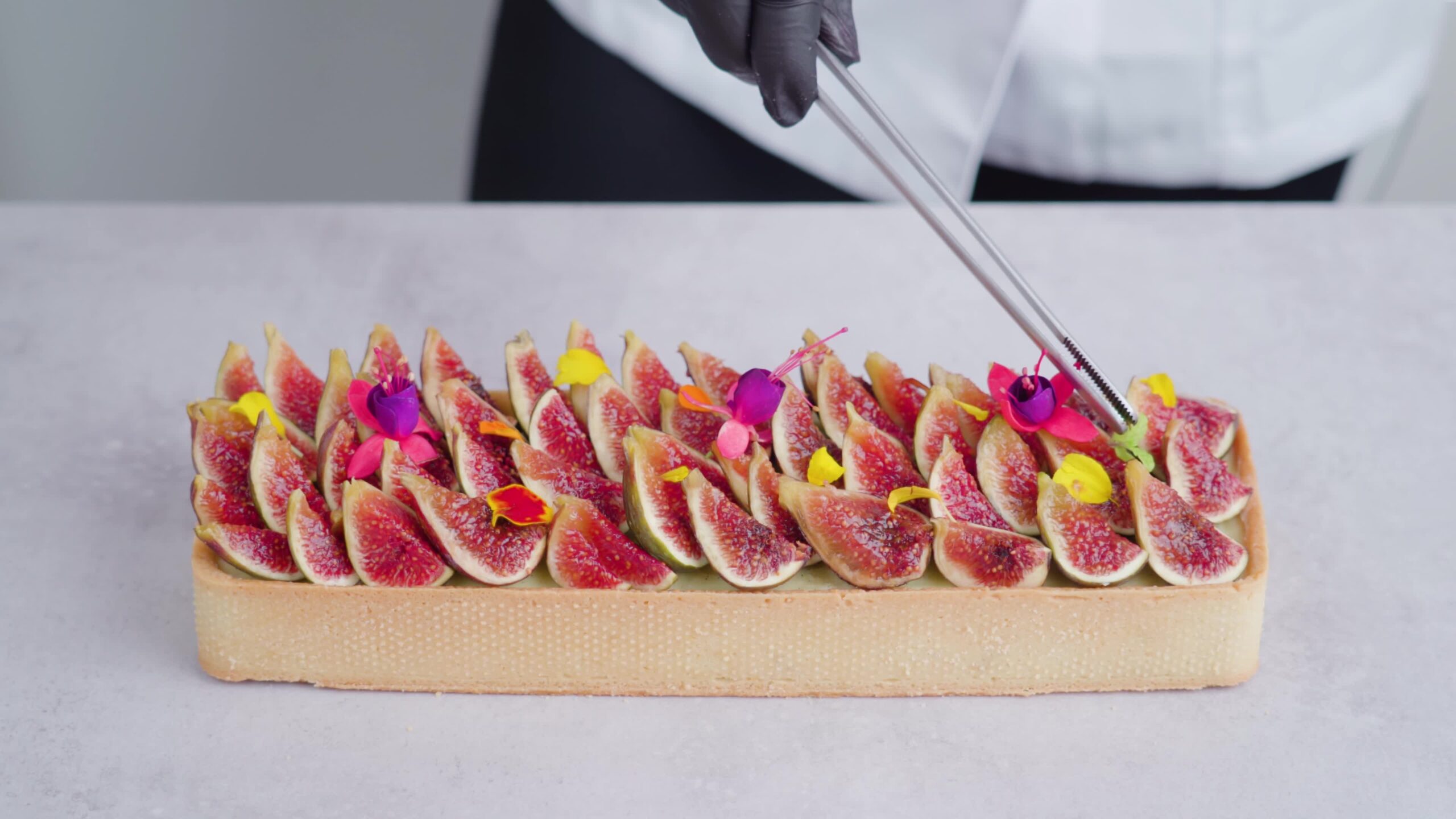 Baker decora un biscotto quadrato chiaro usando una pinza