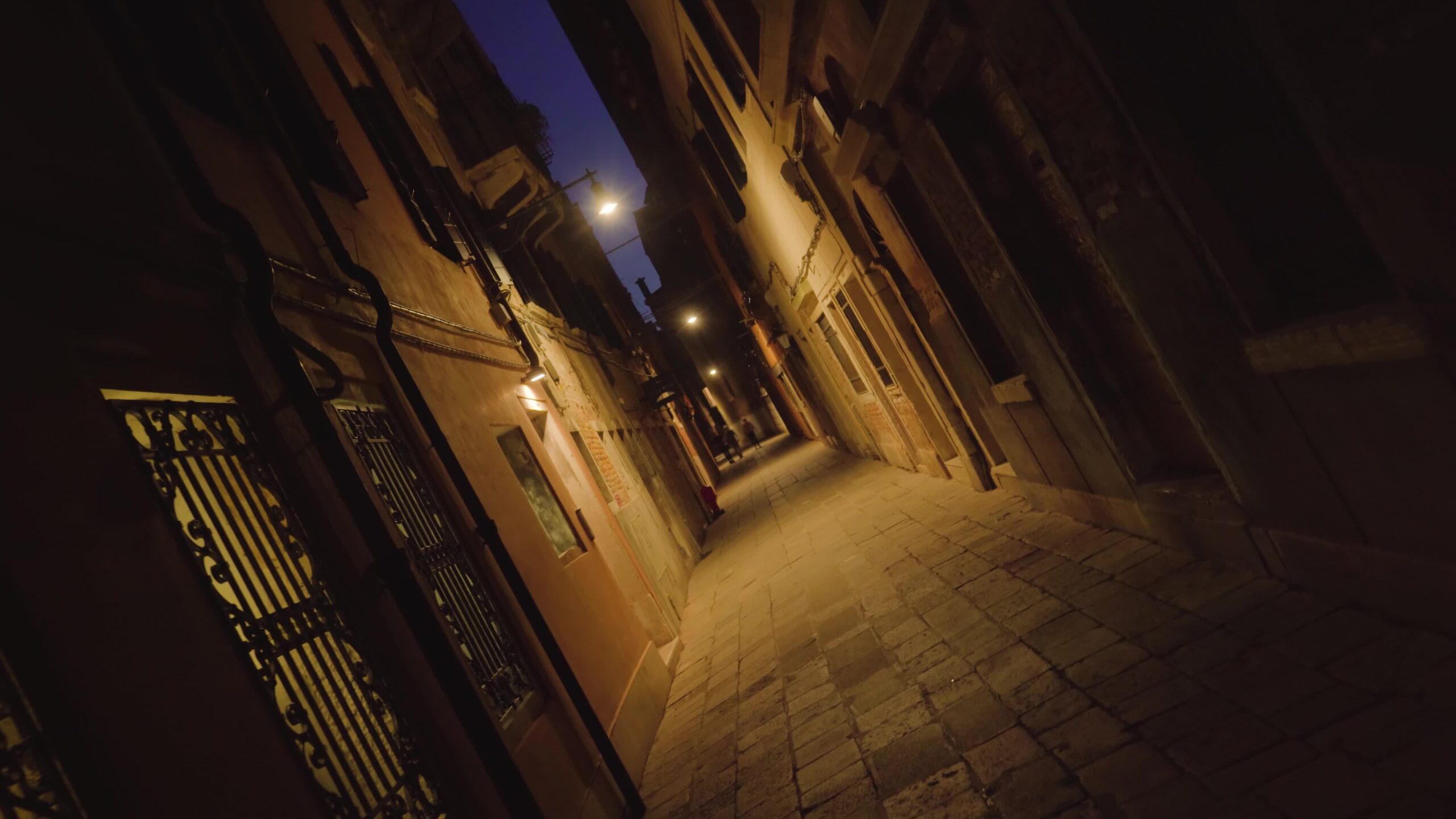 Silhouettes of people walking in narrow Venetian street
