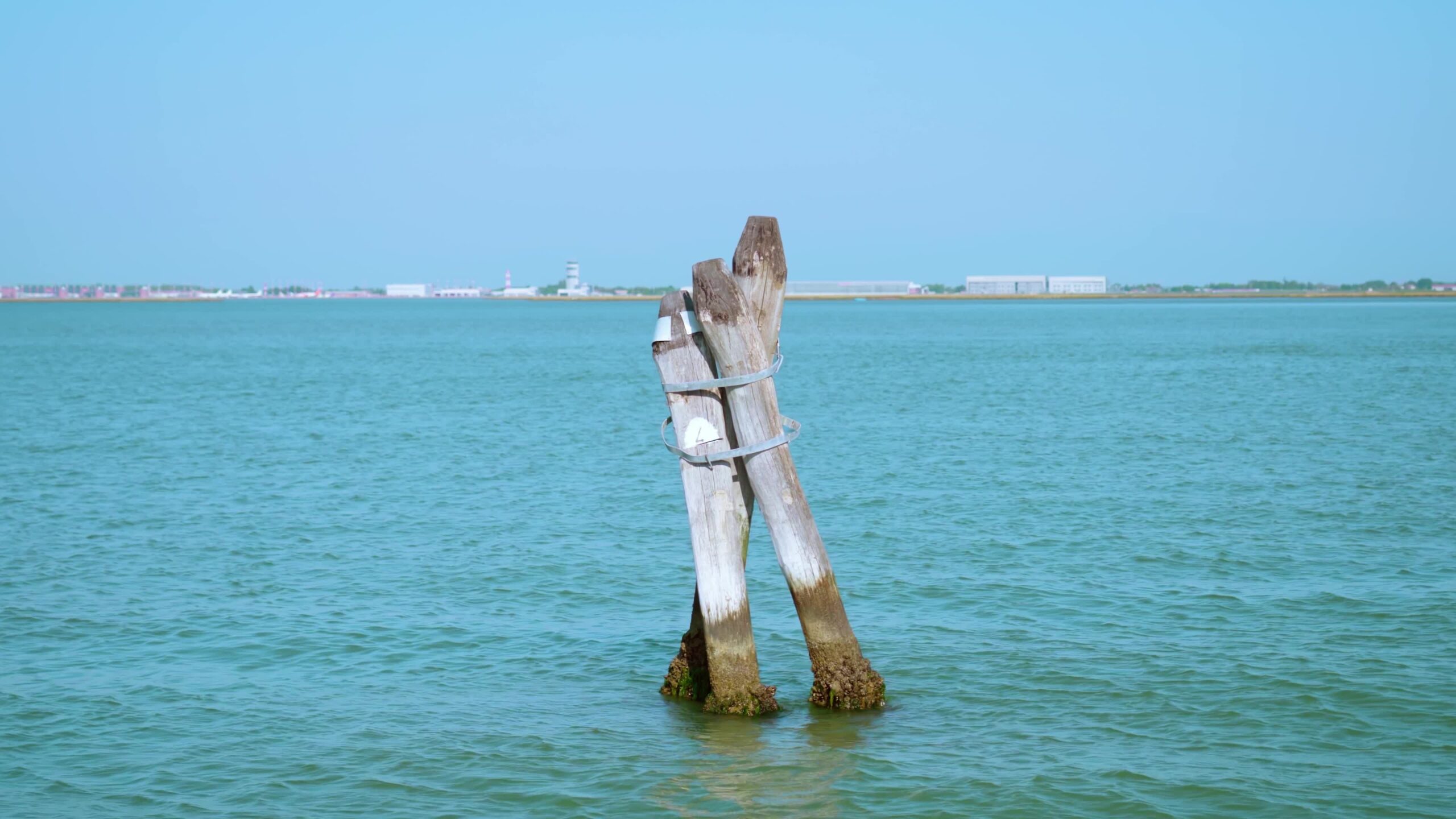 Old wooden channel markers in lagoon against airport
