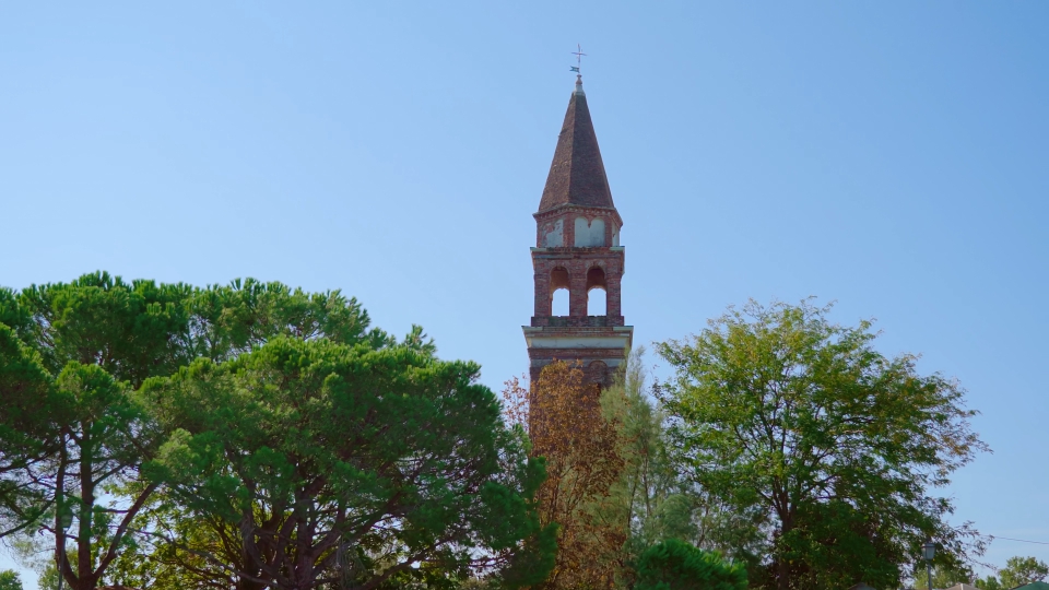 High church bell tower with brick fence stands among park