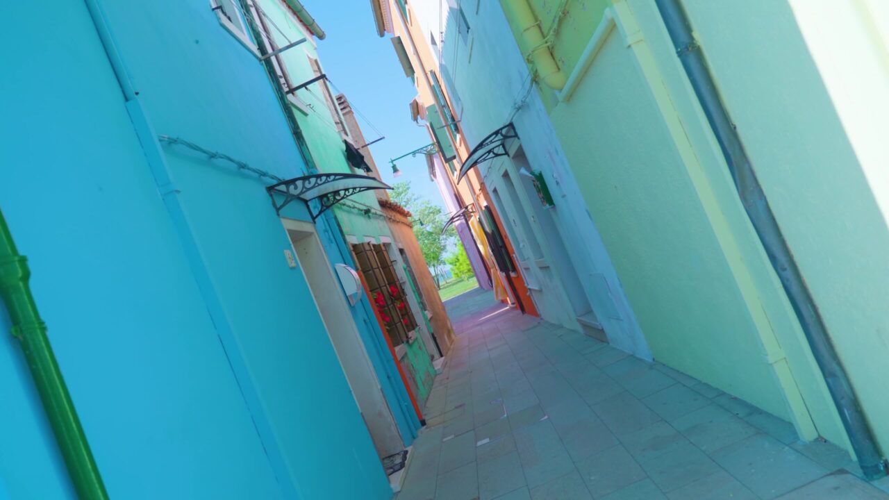 Narrow street between colorful houses in Burano on sunny day