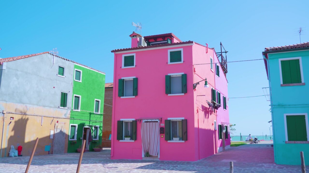 Manless streets of Burano with neat pink house at sunlight