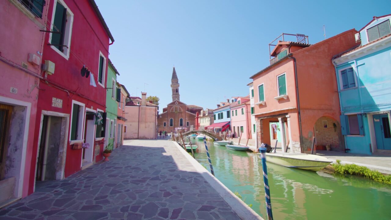 Colorful houses stand along Burano water canal cobbled road