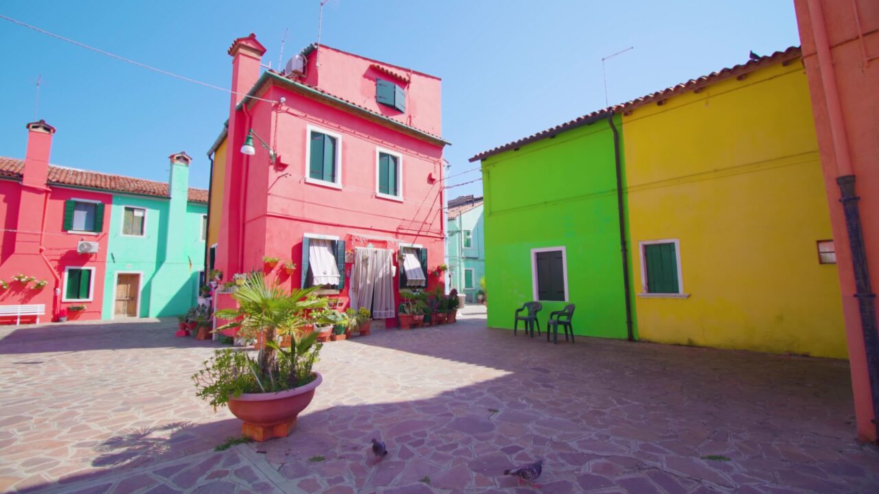 Wide yard with colorful houses lighted by bright sun