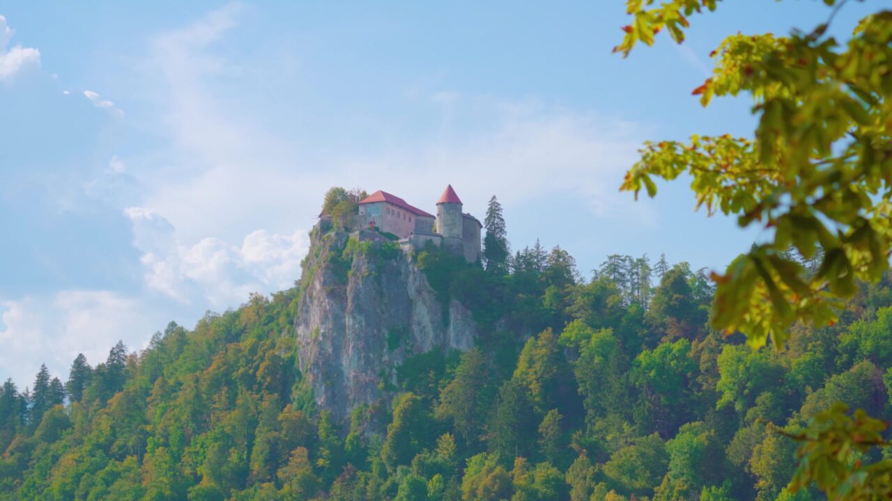 Castello di Bled costruito sulla cima di una scogliera circondato da alberi lussureggianti