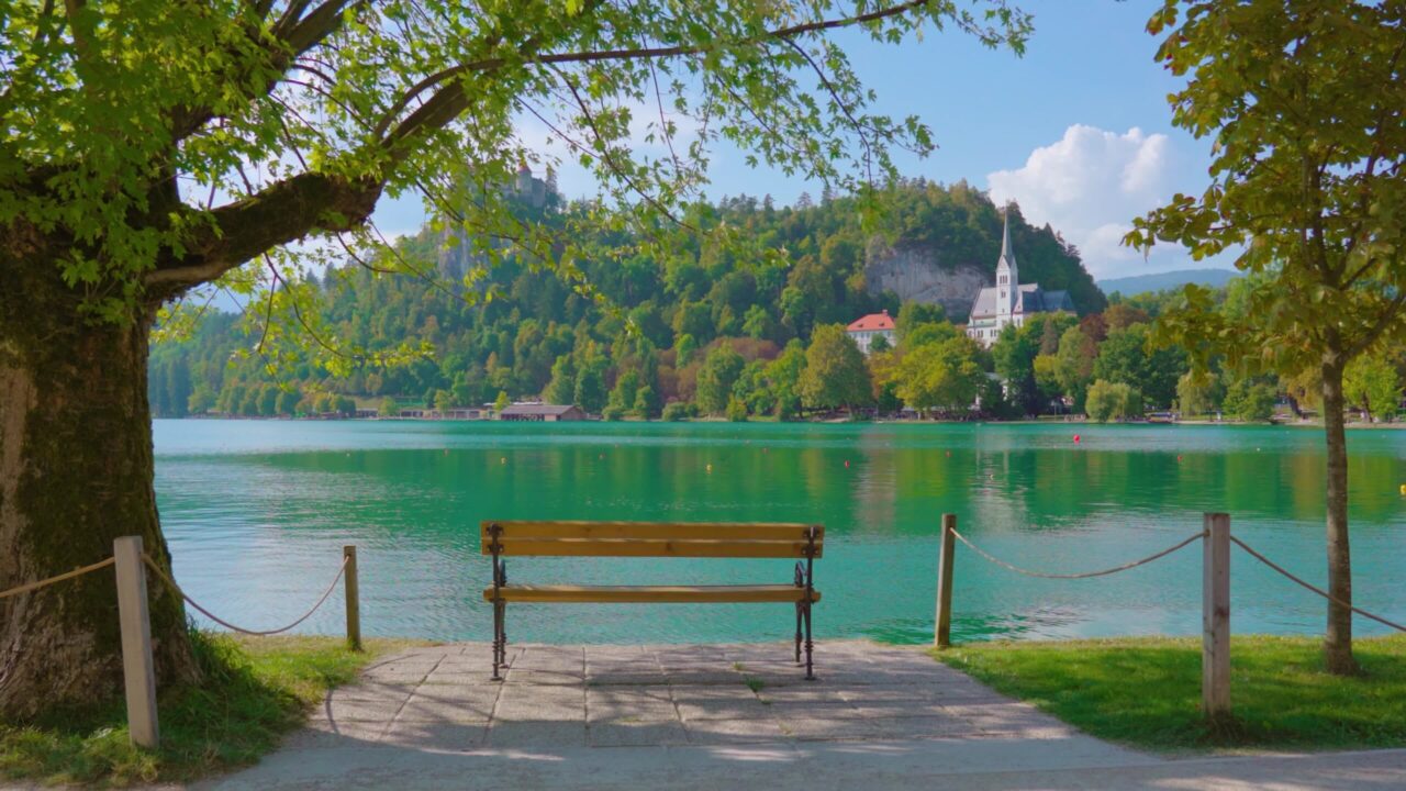 Empty wooden bench overlooking Bled lake and high hill