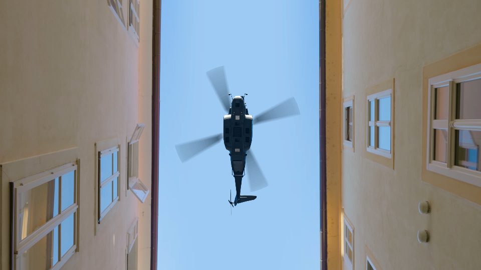 Huge helicopter flies between buildings against blue sky
