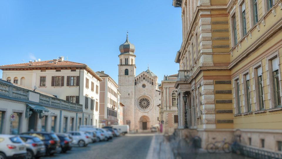 Vintage buildings and cathedral against blue sky in Trento