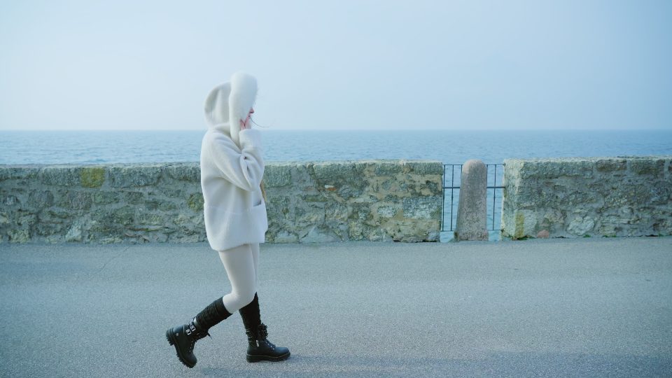 Woman walks on embankment with stone fence against lake