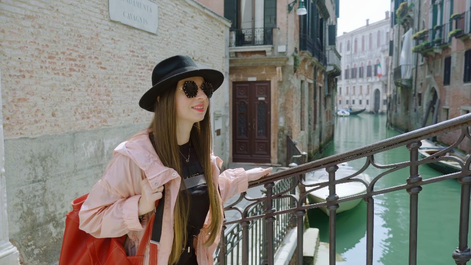 Woman tourist walks on metal bridge over channel in Venice