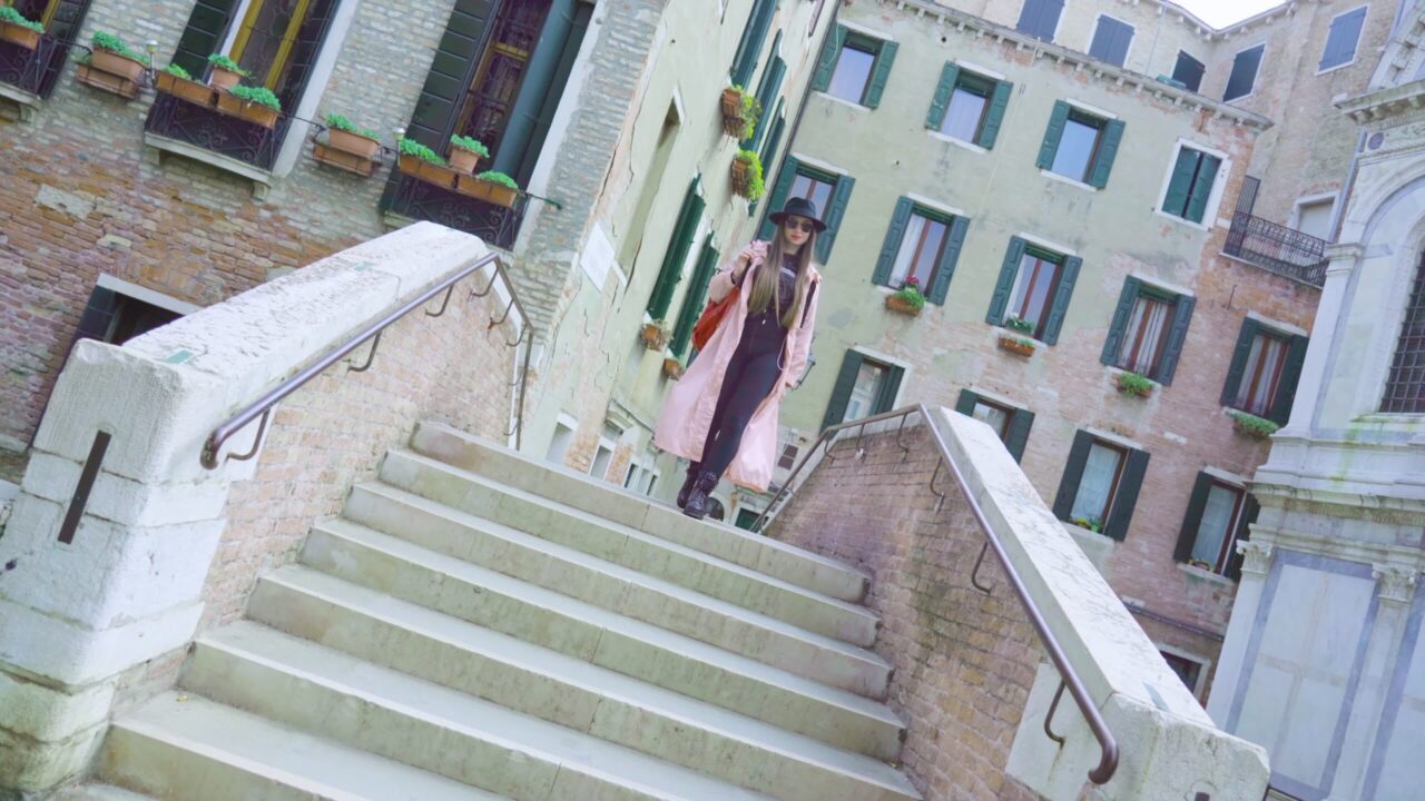 Woman walks on stairs of bridge against vintage buildings