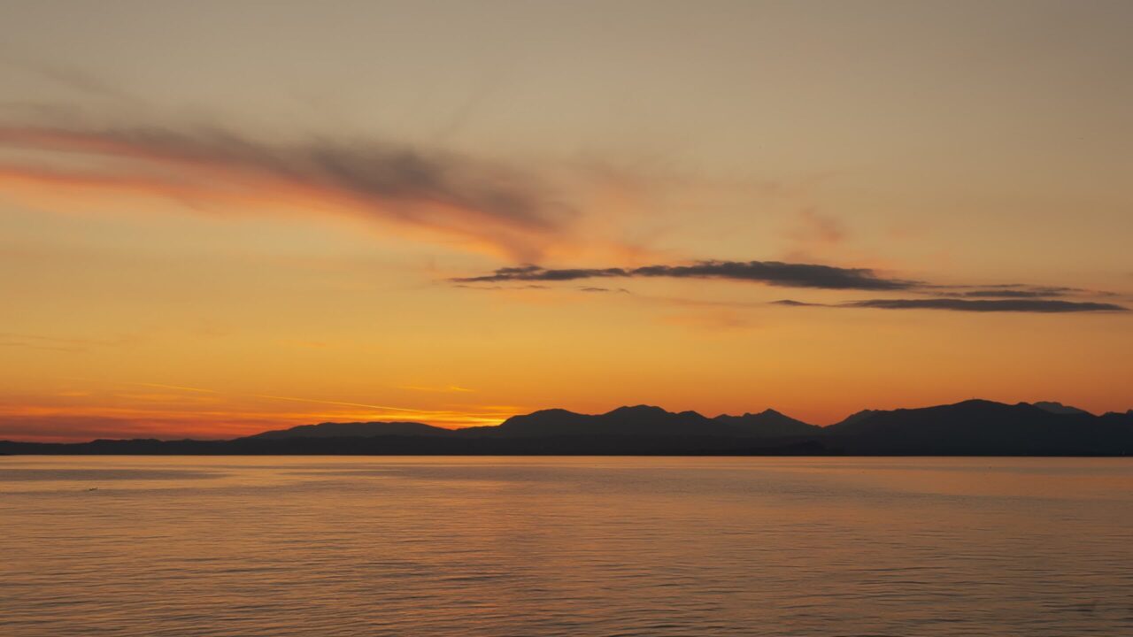 Lake Garda against dark silhouette of mountains at sunset