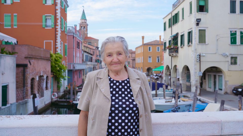 Donna anziana sul canale antico veneziano
