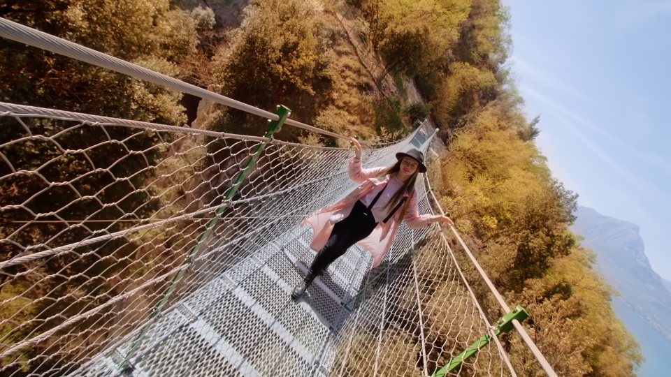 Donna cammina sul ponte sopra gli alberi nel parco
