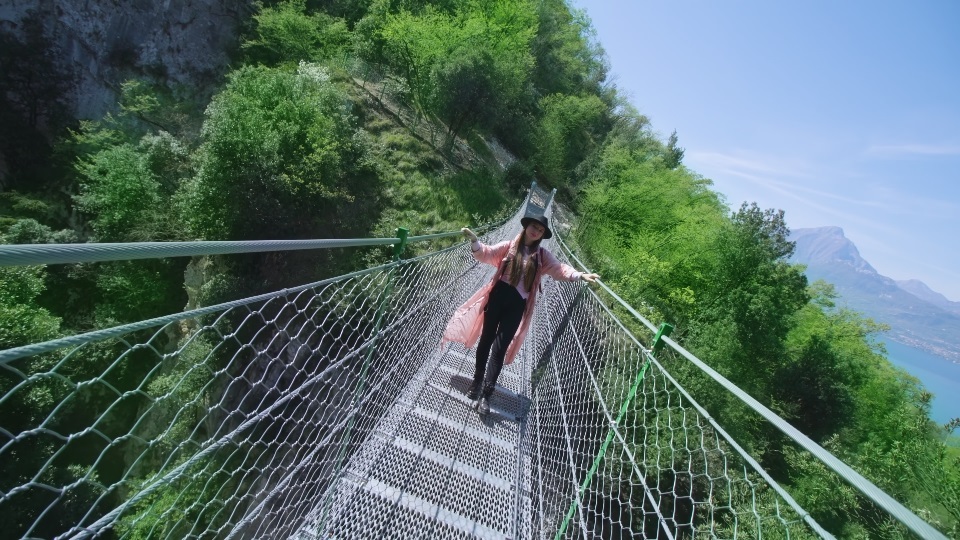 Woman poses for photo standing on bridge against green forest