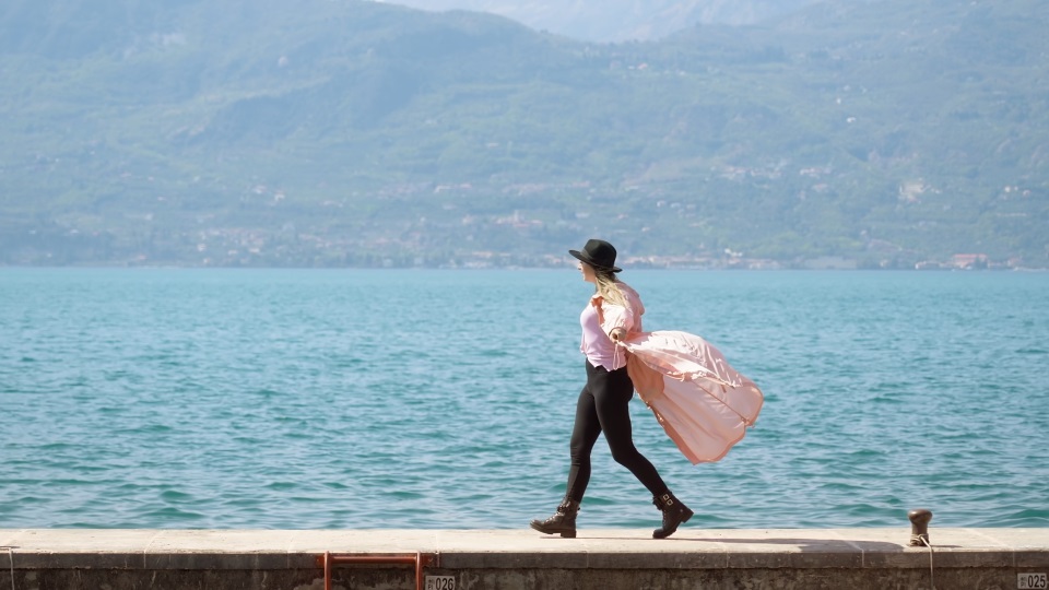 La donna allegra si diverte a camminare sul molo del Lago di Garda ballando