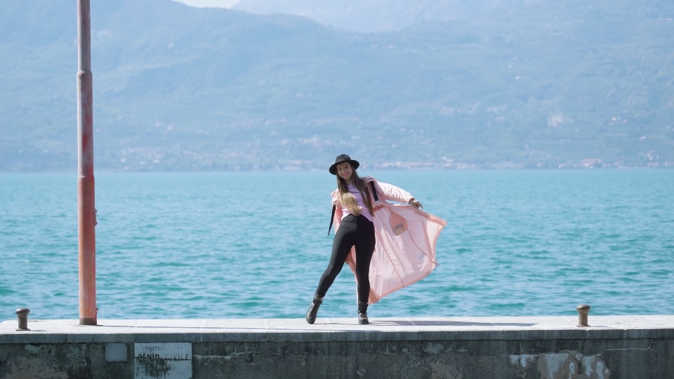 Donna si diverte a ballare sul molo del Lago di Garda con acqua blu