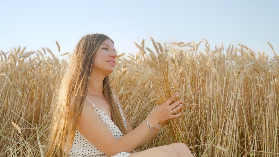 Long-haired woman enjoys making bouquet from wheat spikelets