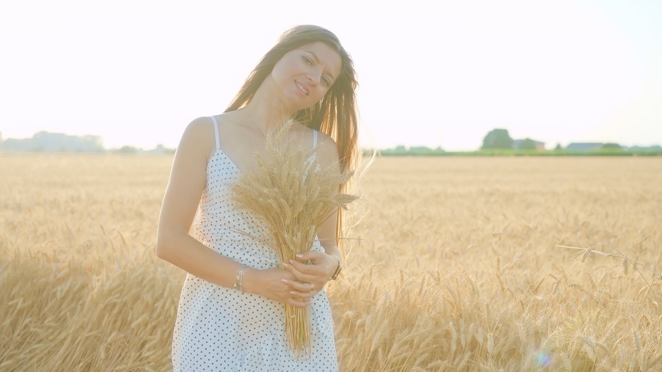 La donna con i capelli lunghi sciolti tiene un bouquet di grano fatto a mano