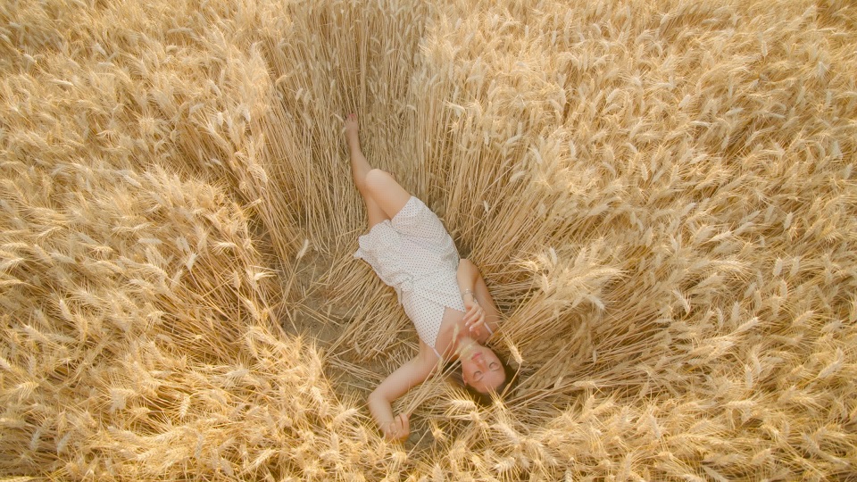 Giovane donna gode di relax nel campo di grano maturo in una giornata di sole