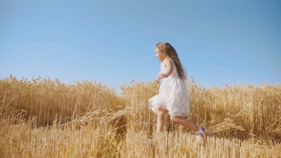 La bambina dai capelli lunghi si diverte a correre nel campo di grano maturo