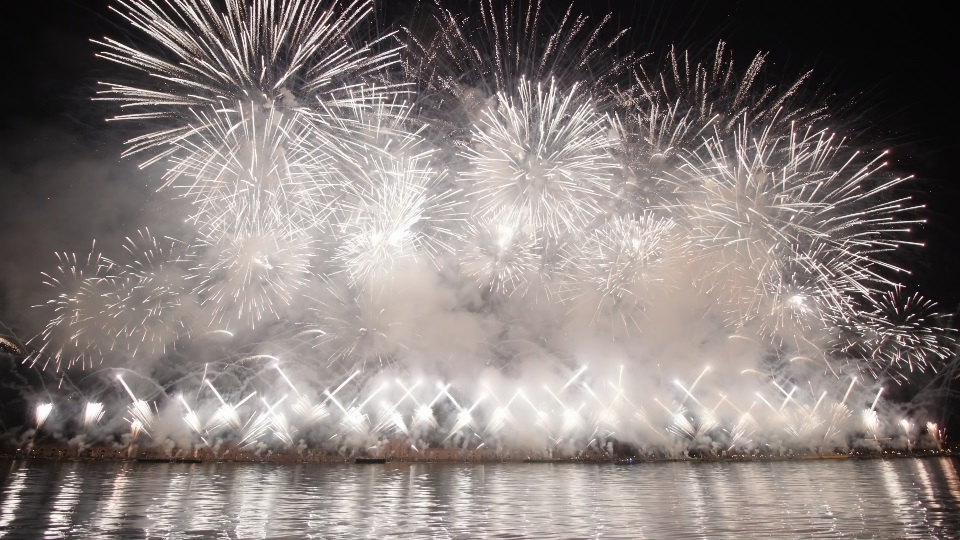 Fuochi d’artificio bianchi scoppiarono nell’aria diffondendo fumo sulla città notturna