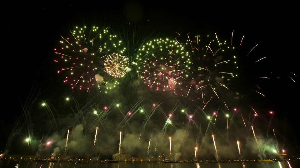 I fuochi d’artificio colorati lanciati nell’aria si riflettono sulla superficie dell’acqua