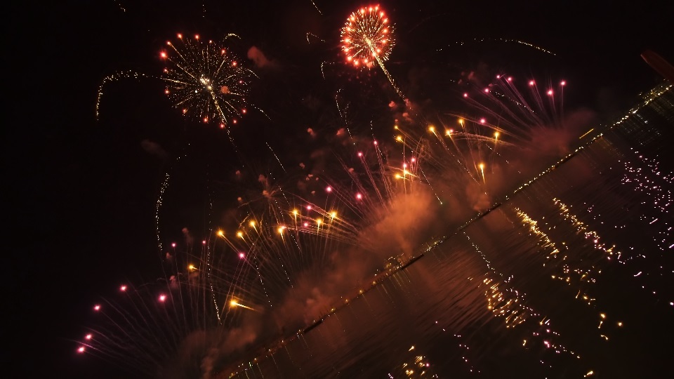 Fuochi d’artificio colorati scoppiano in aria riflettendo sulla superficie dell’acqua