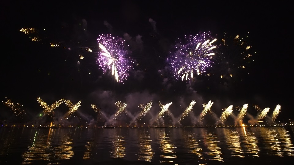 Bright fireworks launched over city reflecting on water
