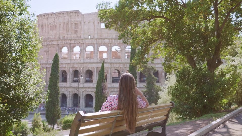 Donna seduta osserva l’antico Colosseo a Roma