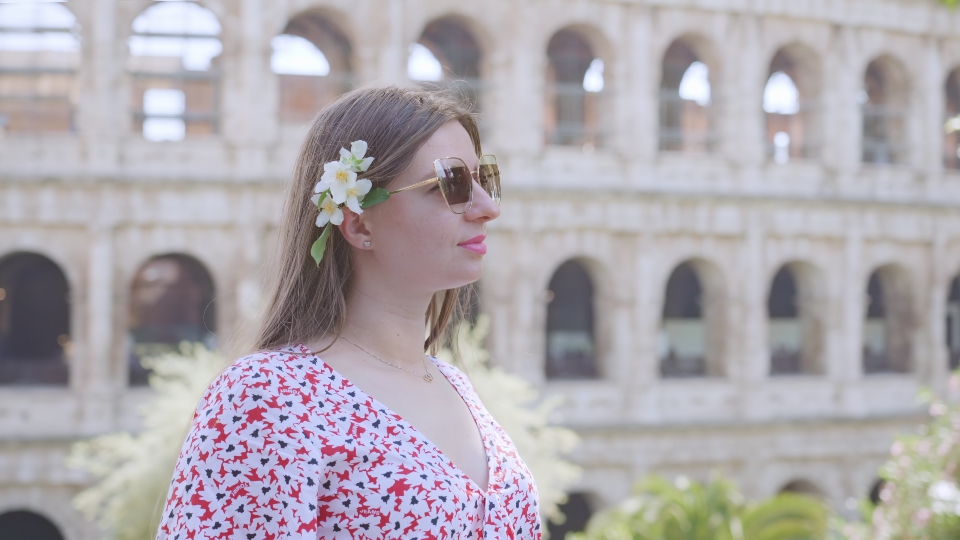 Giovane donna con gli occhiali si erge contro il Colosseo a Roma
